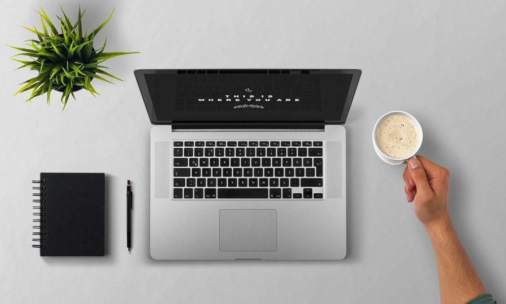 Persoon die een tweedehands laptop nauwkeurig inspecteert op schermkwaliteit en toetsenbord