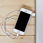 Smartphone op een draadloze oplaadpad met warmte-indicatie, symbool voor batterijslijtage