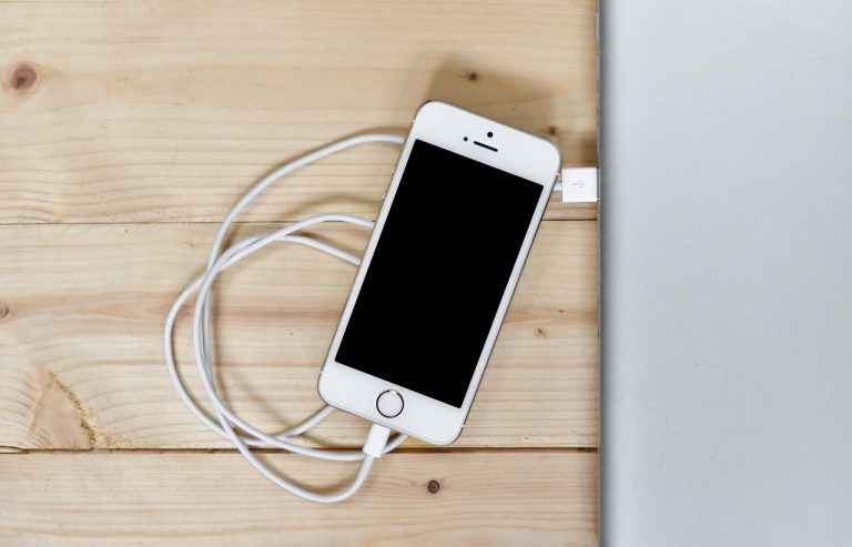 Smartphone op een draadloze oplaadpad met warmte-indicatie, symbool voor batterijslijtage