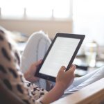 Iemand leest ontspannen op een e-reader in de zon op het strand