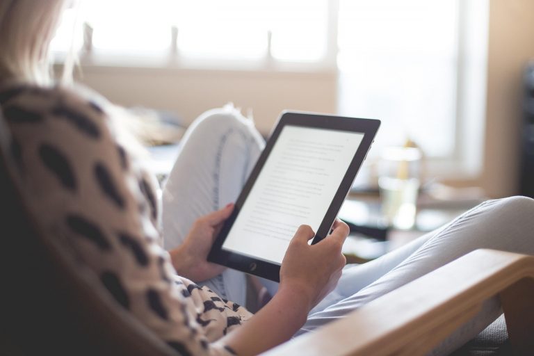 Iemand leest ontspannen op een e-reader in de zon op het strand
