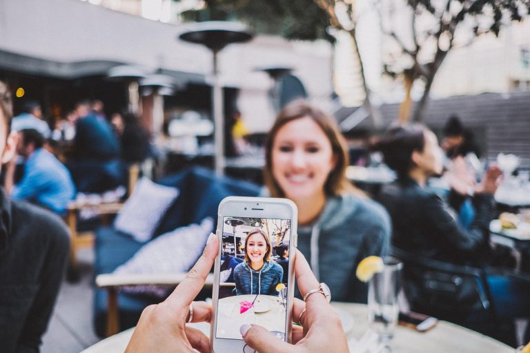 Iemand gebruikt Google Lens op een smartphone om een plant te herkennen in de tuin