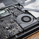 Persoon die gefrustreerd wacht op een trage laptop aan een bureau