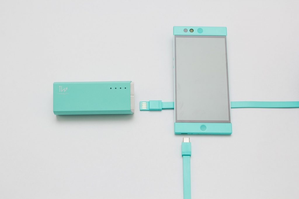 Persoon die een smartphone oplaadt met een powerbank op een zomers festival