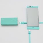 Persoon die een smartphone oplaadt met een powerbank op een zomers festival