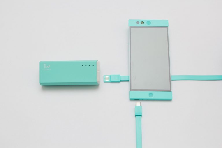 Persoon die een smartphone oplaadt met een powerbank op een zomers festival