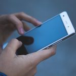 Smartphone met rode batterij-indicator op het scherm die aangeeft dat de accu bijna leeg is