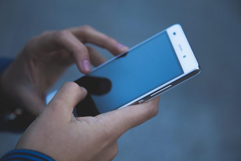 Smartphone met rode batterij-indicator op het scherm die aangeeft dat de accu bijna leeg is