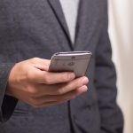 Smartphone op het hete zand op het strand in de zomer, met een oververhittingswaarschuwing op het scherm