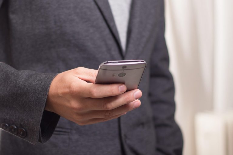Smartphone op het hete zand op het strand in de zomer, met een oververhittingswaarschuwing op het scherm