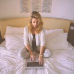 Iemand die een wachtwoordmanager-app gebruikt op een smartphone met een laptop op de achtergrond