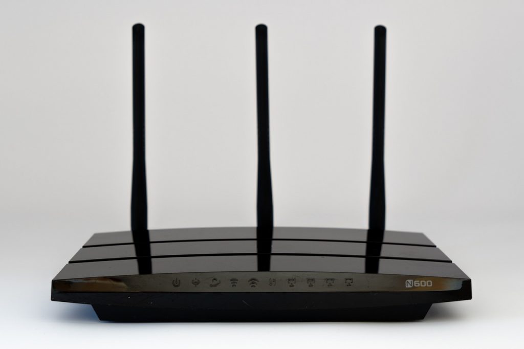 Thuisrouter op een bureau met beveiligingsinstellingen op een laptop op de achtergrond