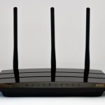 Thuisrouter op een bureau met beveiligingsinstellingen op een laptop op de achtergrond