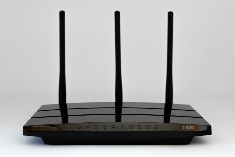 Thuisrouter op een bureau met beveiligingsinstellingen op een laptop op de achtergrond