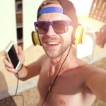 Persoon die met koptelefoon muziek luistert en een playlist samenstelt op zijn laptop