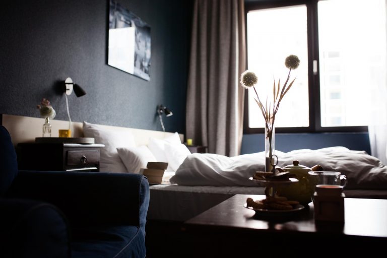 Een draadloze speaker op een hotelkamertafel naast een smartphone