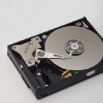 Close-up van een harde schijf naast een computerscherm met diagnostische software