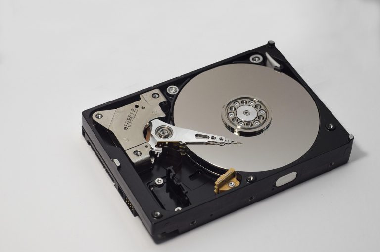 Close-up van een harde schijf naast een computerscherm met diagnostische software