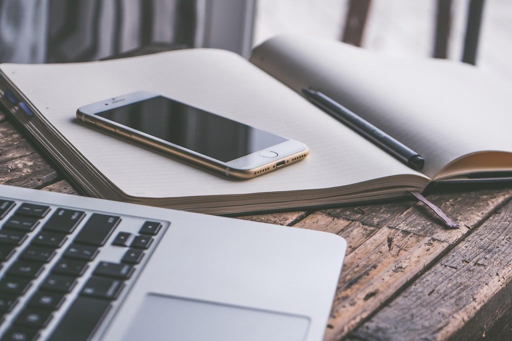 Iemand houdt een smartphone vast om een presentatie op een laptop te bedienen in een vergaderzaal