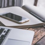 Iemand houdt een smartphone vast om een presentatie op een laptop te bedienen in een vergaderzaal