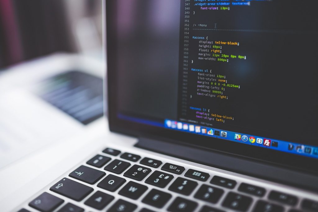 Persoon die op een laptop drie verschillende website-ontwerpen vergelijkt aan een modern bureau
