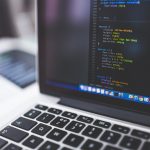 Persoon die op een laptop drie verschillende website-ontwerpen vergelijkt aan een modern bureau