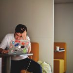 Persoon die gefrustreerd naar een laptop kijkt tijdens het invullen van een online vragenlijst