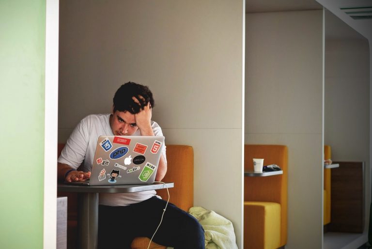 Persoon die gefrustreerd naar een laptop kijkt tijdens het invullen van een online vragenlijst