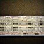 Een transistor aangesloten op een breadboard met weerstanden en een LED, klaar voor een beginnerscircuit